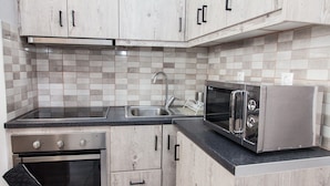 A kitchen with wooden cabinets, a stainless steel oven, a microwave, and a sink. - Cozy and Comfy Central Athens Apt. (Athens)