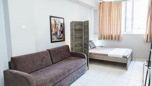 A modern room with a brown sofa, a bed with a white mattress, a painting on the wall, and a window with curtains. - Cozy and Comfy Central Athens Apt. (Athens)