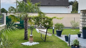 Un jardin bien entretenu, agrémenté d’un hamac, de plantes en pot et d’un petit vase décoratif.