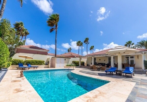 A swimming pool with lounge chairs and palm trees.