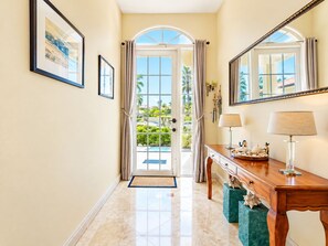 A hallway with a wooden bench, a mirror, and a door leading to a balcony with a view of greenery.