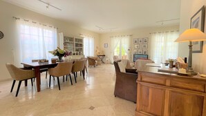 A spacious living area with a dining table, chairs, a sofa, and a TV. - Slice of Heaven at Tierra Del Sol - Sleeps 6 - Private Pool - On Golf Course (Noord)