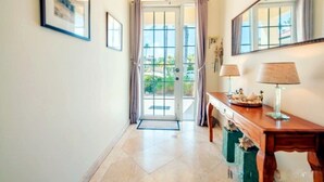 A hallway with a wooden bench, a lamp, and a door leading to a balcony. - Slice of Heaven at Tierra Del Sol - Sleeps 6 - Private Pool - On Golf Course (Noord)