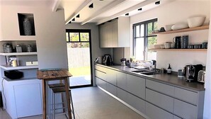Une cuisine moderne dotée d’un îlot central, de meubles encastrés et d’une fenêtre laissant entrer la lumière naturelle.