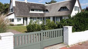 Une maison moderne avec un toit en pente, une façade blanche et un portail vert.