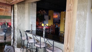 A bar area with a black countertop, bar stools, and a fan. - Waterfront 4 bedroom. Discount available for extended or monthly rentals! (Slidell)