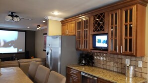 A kitchen with wooden cabinets, a stainless steel refrigerator, a built-in oven, a dishwasher, a granite countertop, and a television mounted above the cabinets. - Waterfront 4 bedroom. Discount available for extended or monthly rentals! (Slidell)