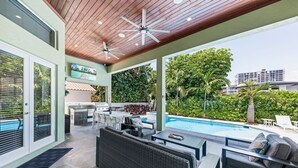 An outdoor patio with a pool, seating area, and a kitchen.