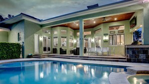 A swimming pool with a covered patio area, outdoor seating, and a view of the pool.
