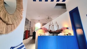 A modern living room with a blue and white striped ceiling, a round mirror, a blue cabinet, and a wooden ceiling fan. - [SEA VIEW] On three floors with garden (Falerna Marina)