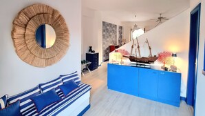 A modern living room with a blue and white striped sofa, a round mirror, and a blue cabinet with decorative items. - [SEA VIEW] On three floors with garden (Falerna Marina)