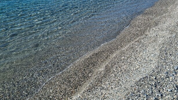 A clear view of a pebble beach leading to calm waters under a clear blue sky. - [SEA VIEW] On three floors with garden (Falerna Marina)