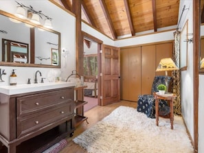 A bathroom with a wooden vanity, a large mirror, and a fluffy rug.