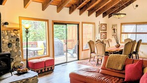 Ein geräumiges Wohnzimmer mit Kamin aus Stein, einer Ledersofa und einem Essbereich mit Stühlen und Tisch.