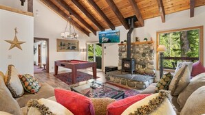 Ein gemütliches Wohnzimmer mit Kamin aus Stein, Holzbalkendecke und Billardtisch.
