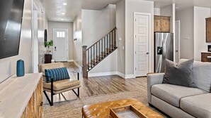 A spacious living room with a sofa, a coffee table, and a TV mounted on the wall. - Red Mountain Springs, GORGEOUS VIEWS, GREAT COMMUNITY POOL! (Santa Clara)