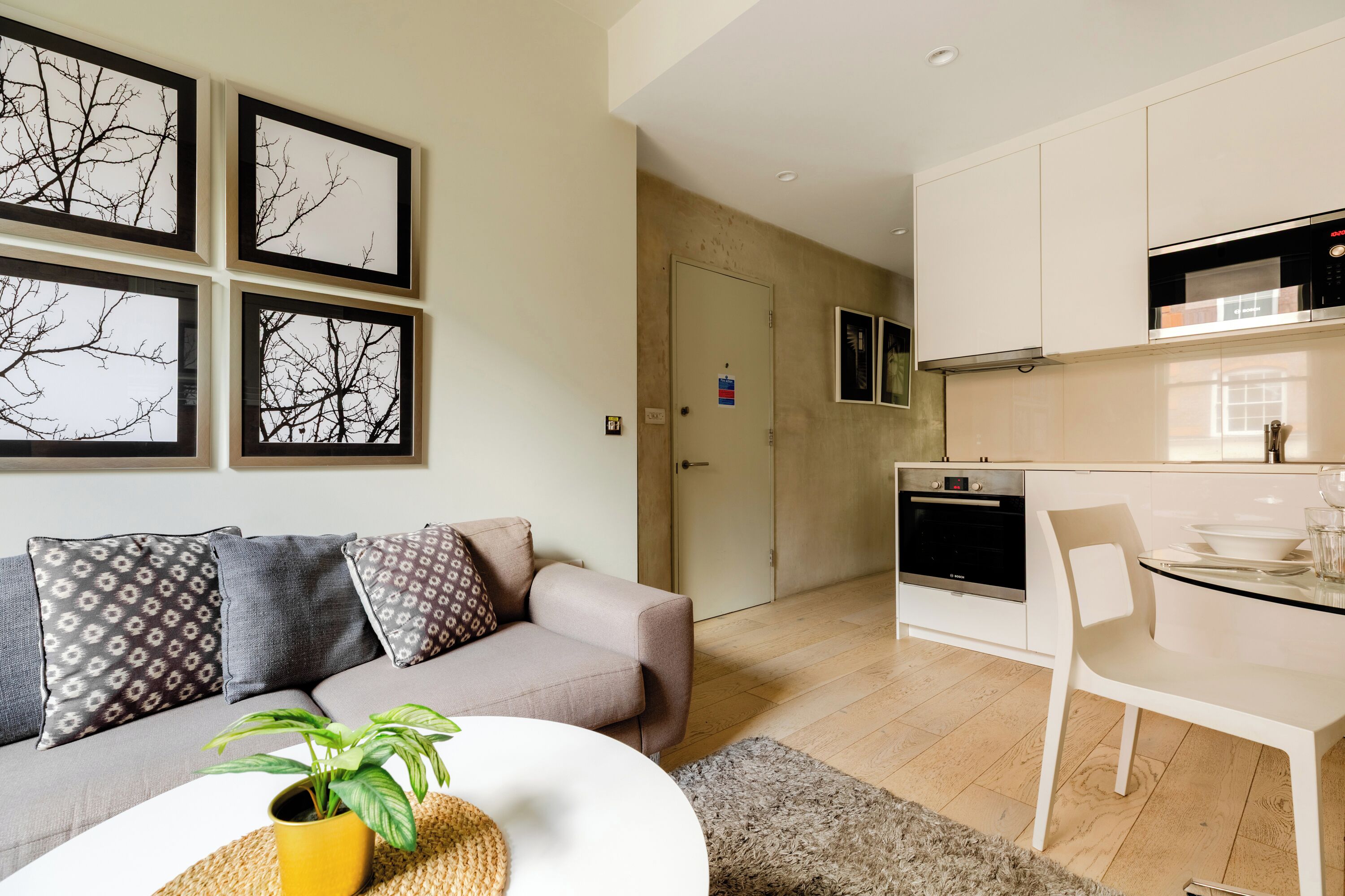 Un salon moderne comprenant un canapé, une table à manger et un coin cuisine avec des placards et des appareils électroménagers.