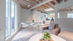 Un salon moderne avec un canapé, une table basse agrémentée d’une plante, et un coin repas comprenant des chaises et une table.