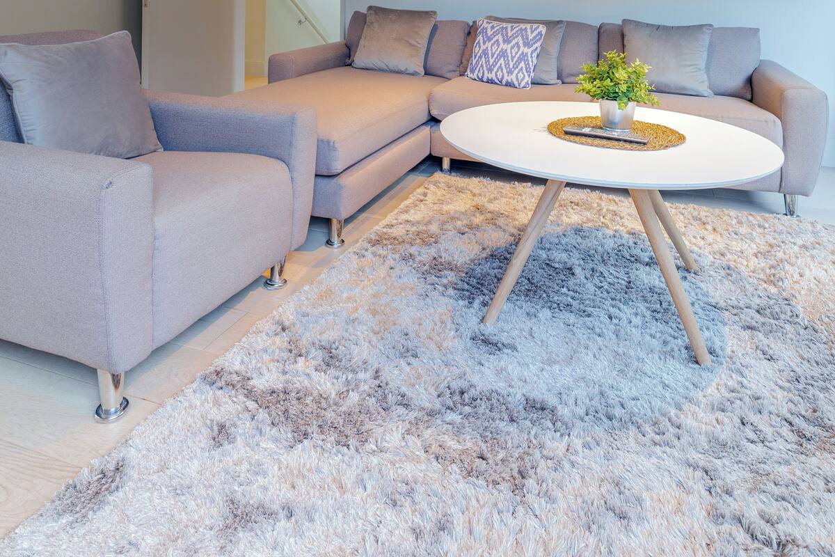 A modern living room with a sectional sofa, a round coffee table, and a fluffy rug.