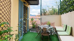 A small patio with a table and chairs, a sofa, and a potted plant. - Happyfew La Providence (Nice)