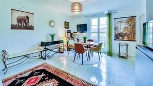 A spacious living room with a dining area, a television, and artwork on the walls. - Happyfew La Providence (Nice)