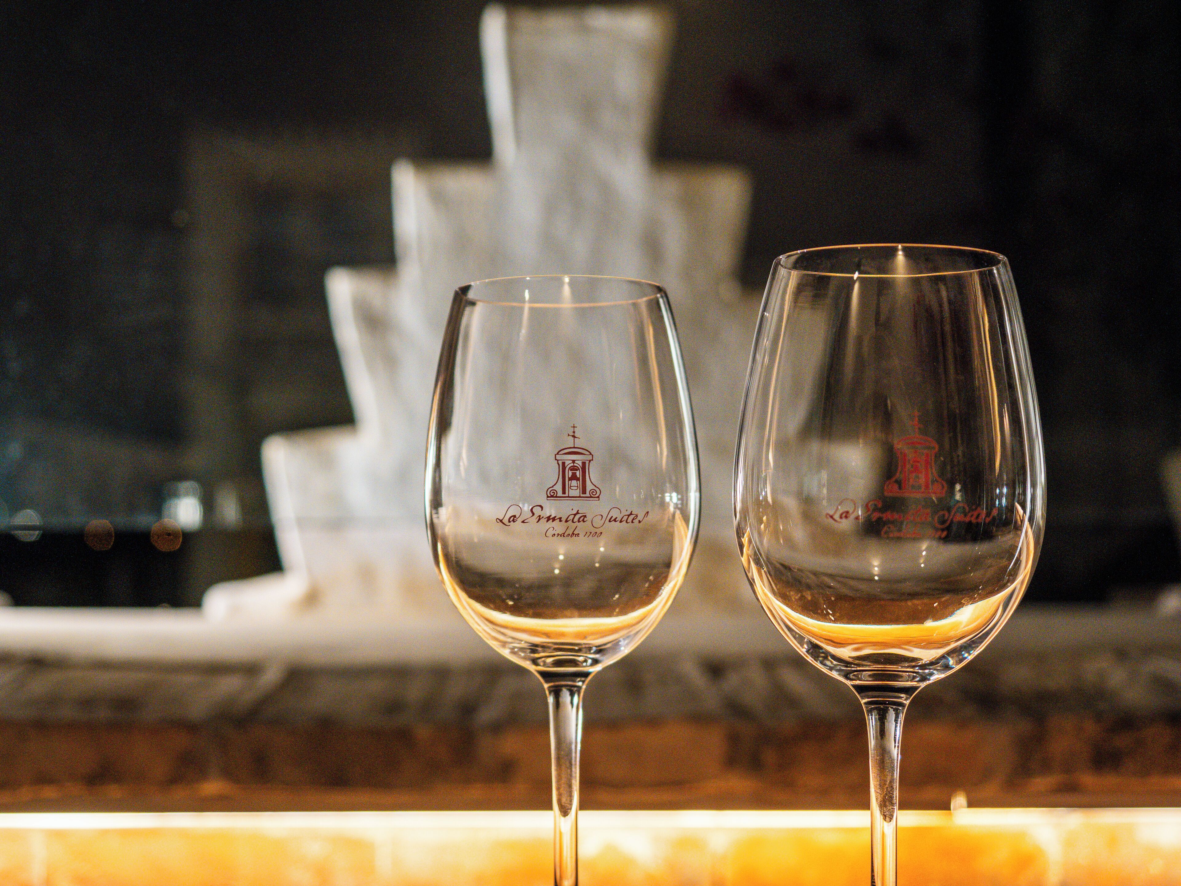 Dos copas de vino con una fuente al fondo.