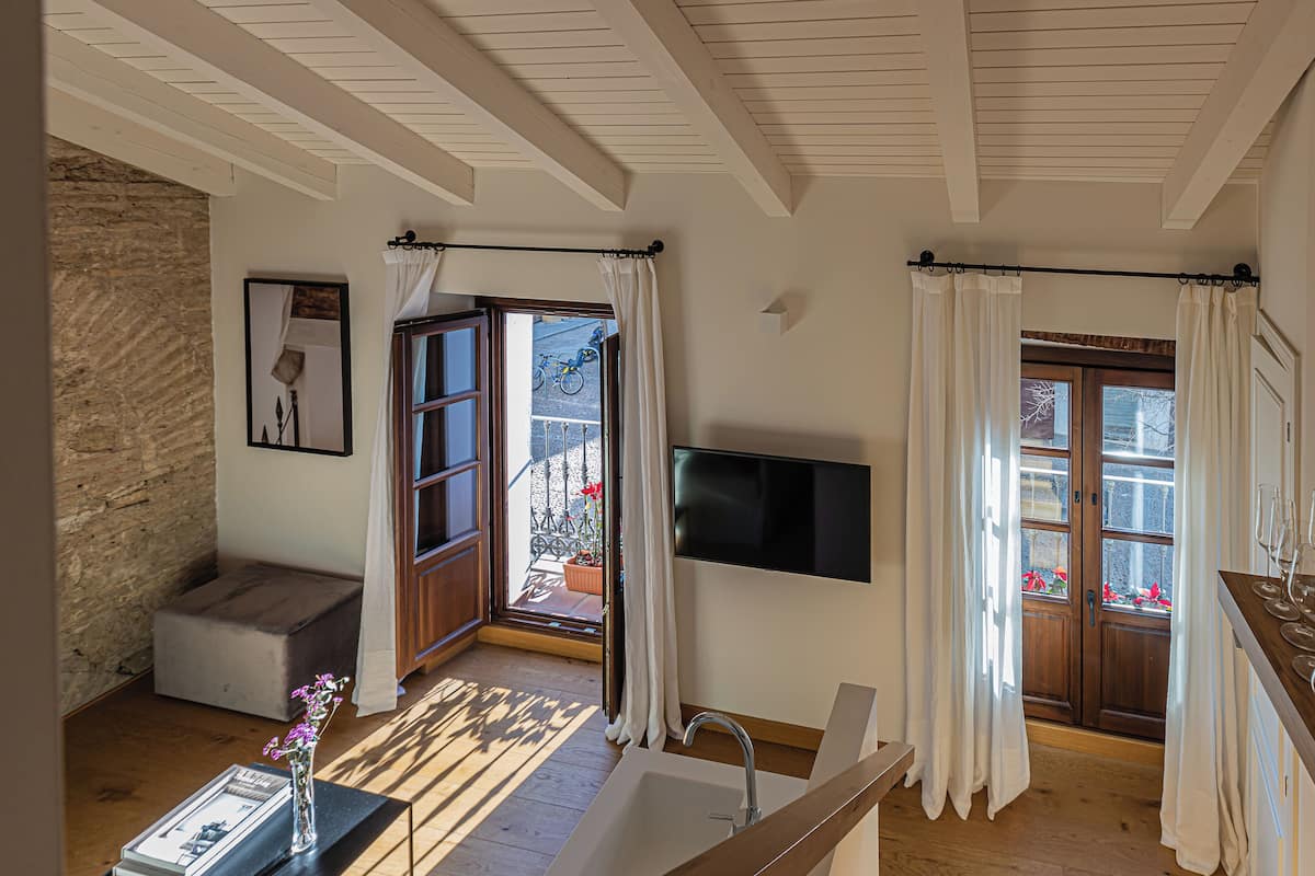 Un baño moderno con una bañera grande, un banco de madera y una ventana con cortinas.