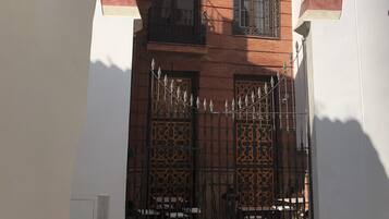A building with a white facade, a red and white striped archway, and a black metal gate.
