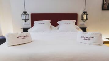Habitación de hotel con una cama grande, dos mesitas de noche y dos lámparas colgantes.