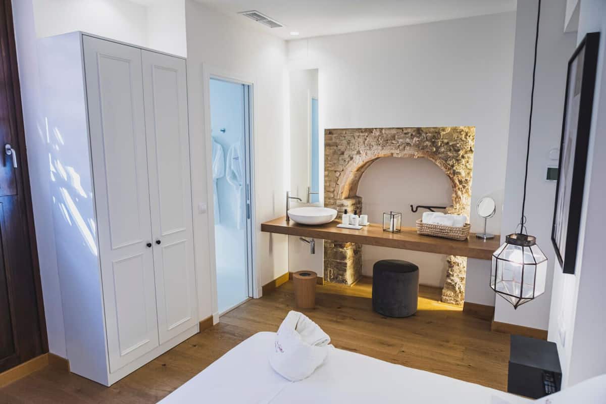 Un baño moderno con pared de arco de piedra, tocador de madera y un espejo grande.