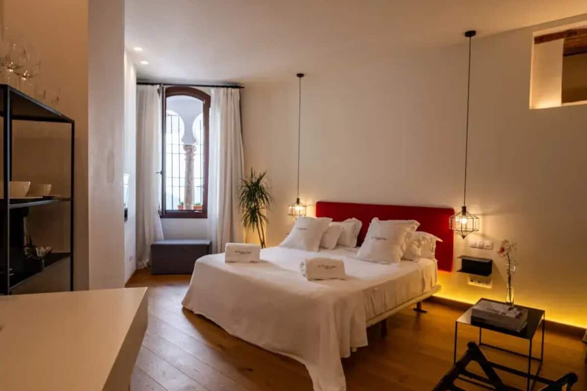 Una habitación de hotel con una cama grande, mesitas de noche, un escritorio y una silla.