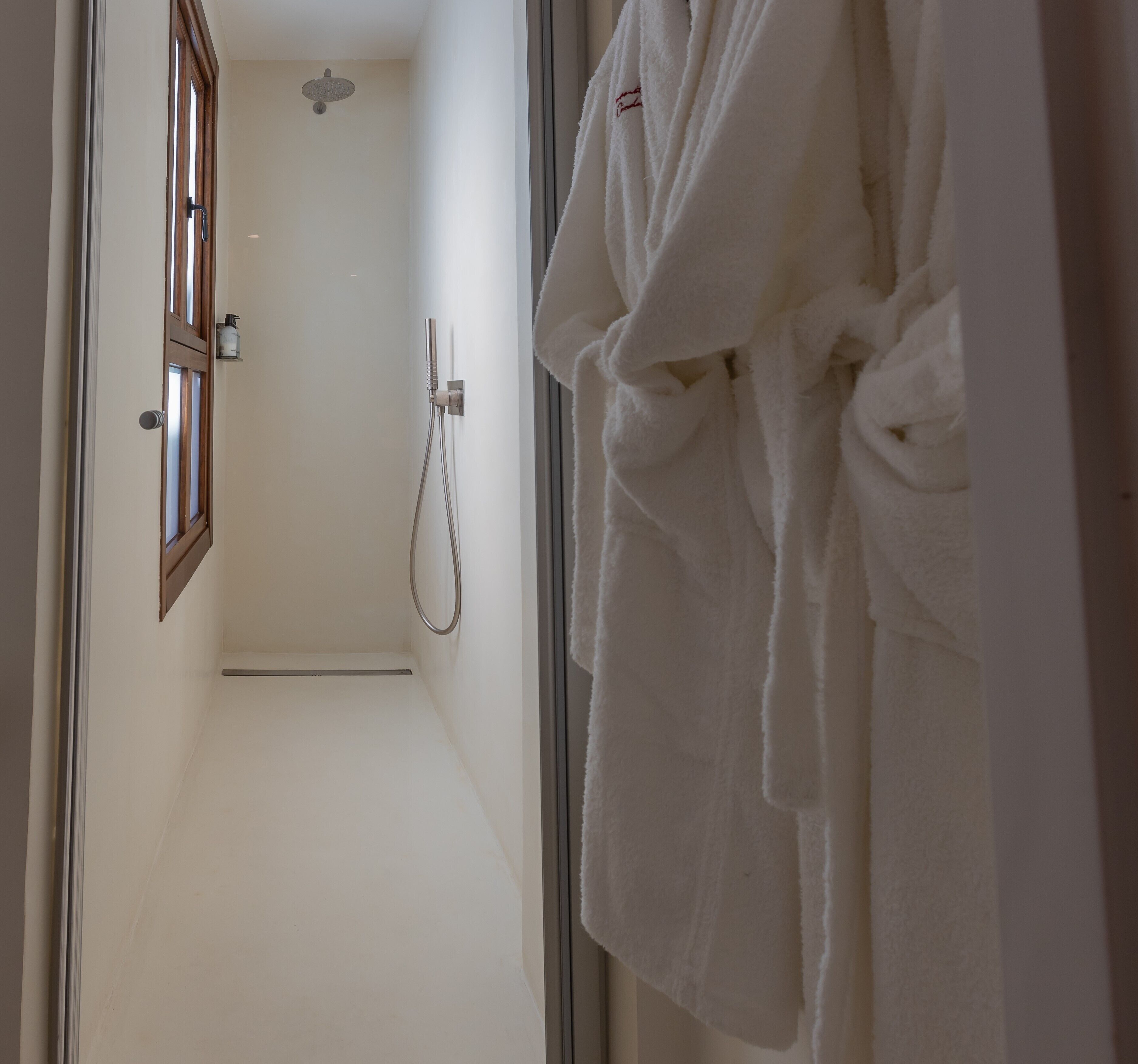 Ein Badezimmer mit Dusche, Handtuchhalter und einer Tür mit Fenster.