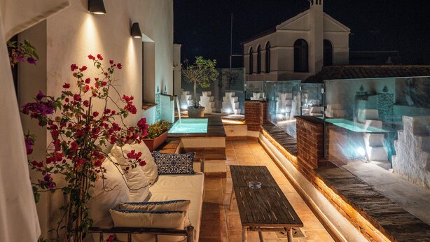 Eine Außenpatio-Terrasse mit Sitzgelegenheit, einem Springbrunnen und Blick auf ein Gebäude mit Rundbogenfenstern.