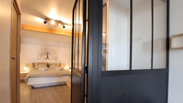 A bedroom with a bed, bedside table, and a wall-mounted light fixture.