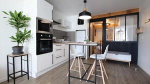 A modern kitchen with white cabinets, a black oven, and a dining area with a bench and two chairs.