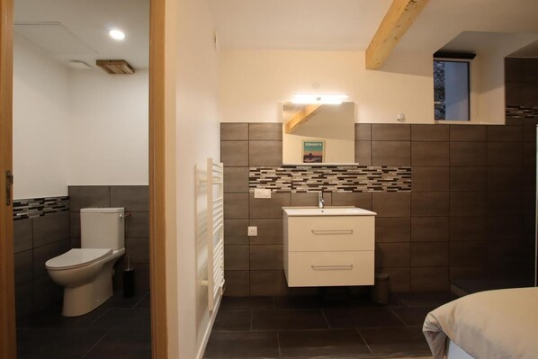 Un baño moderno con inodoro, lavamanos y espejo.