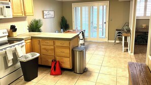 A kitchen with wooden cabinets, a microwave, a stove, and a trash can.