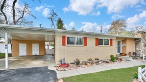 A single-story house with a covered garage, a front porch with outdoor seating, and a well-maintained lawn.