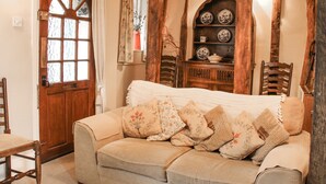 A cozy room with a wooden door, a cushioned sofa, and a wooden cabinet with dishes. - 55 Corve Street (Ludlow)