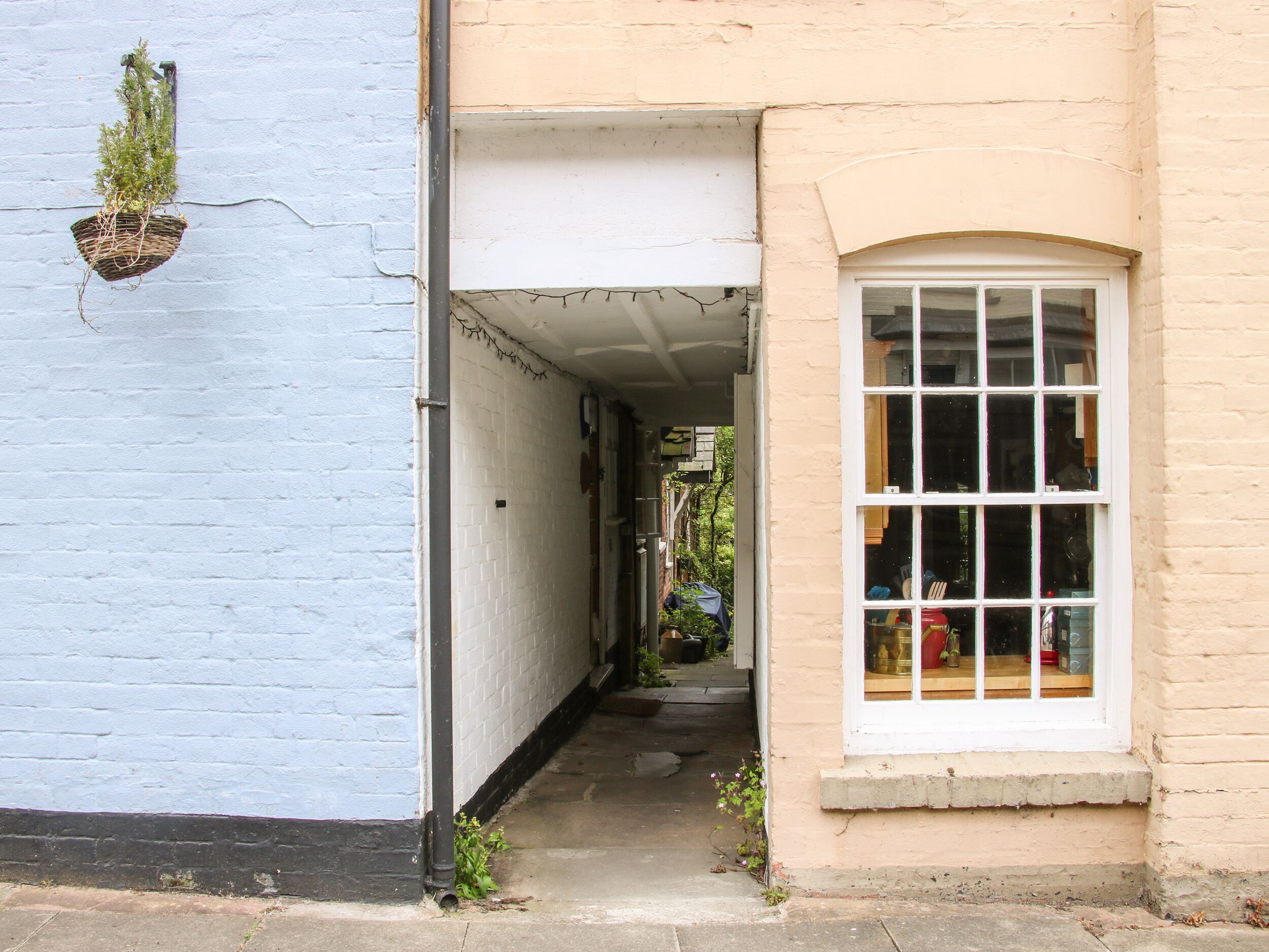 Une ruelle étroite, avec un immeuble bleu sur la gauche et un immeuble beige sur la droite.