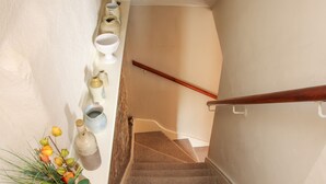 A staircase with a wooden handrail, beige walls, and a series of ceramic containers on the wall. - 55 Corve Street (Ludlow)