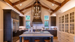 Una cocina amplia con una isla central, armarios de madera oscura, electrodomésticos de acero inoxidable y un ventanal que proporciona luz natural.