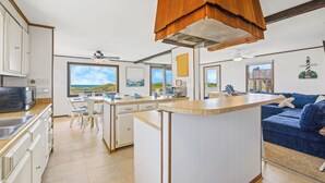 A modern kitchen with a central island, white cabinetry, and a view of the beach. - Oceanfront Dog Friendly Home w/ Hot Tub, Smart TVs, Community Walkway to Beach (Hatteras)