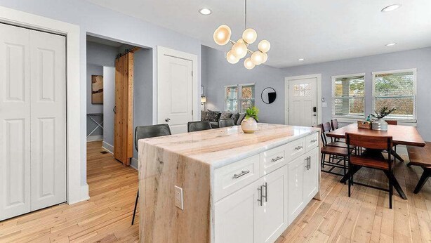 A modern kitchen with a large island, white cabinetry, and a dining area with a wooden table and chairs. - City Oasis with Hot Tub Group-Friendly (Atlanta)