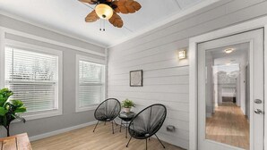 A room with white paneled walls, a wooden floor, a ceiling fan, and a door leading to another room. - City Oasis with Hot Tub Group-Friendly (Atlanta)