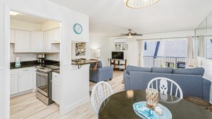 Une cuisine moderne avec des meubles blancs, une cuisinière et un coin repas comprenant une table et des chaises.