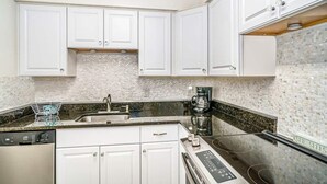 Une cuisine moderne avec des meubles blancs, un plan de travail en granit, un lave-vaisselle et une cuisinière intégrée.