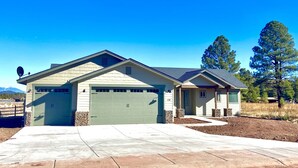 A single-story house with a garage, a stone foundation, and a clear driveway. - *** Double MASTER Cabin *** Walk to Lake and Golf Course (Williams)