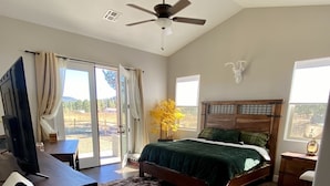 A bedroom with a bed, a desk, a ceiling fan, and a view of the outdoors. - *** Double MASTER Cabin *** Walk to Lake and Golf Course (Williams)
