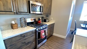 A modern kitchen with wooden cabinets, stainless steel appliances, and a granite countertop. - *** Double MASTER Cabin *** Walk to Lake and Golf Course (Williams)